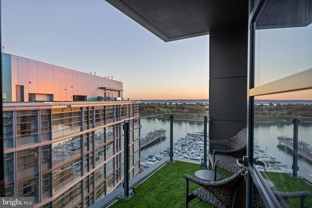 balcony at dusk featuring a water view