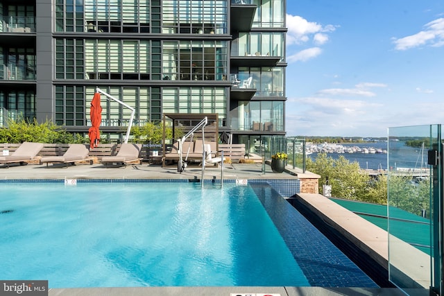 view of pool with a water view and a patio area