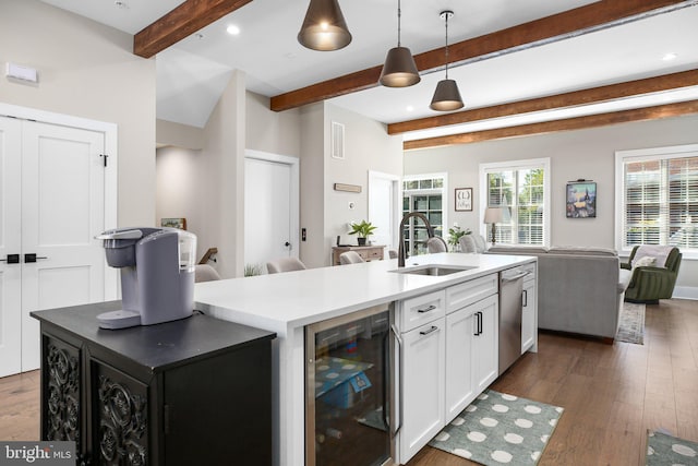 kitchen with a kitchen island with sink, dark hardwood / wood-style floors, beverage cooler, sink, and white cabinetry