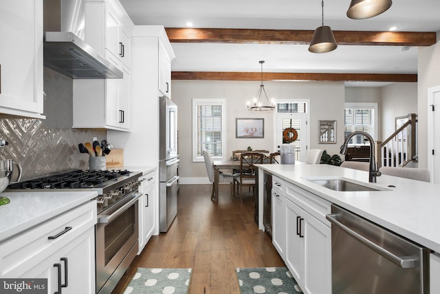 kitchen featuring pendant lighting, sink, high end appliances, dark wood-type flooring, and wall chimney range hood