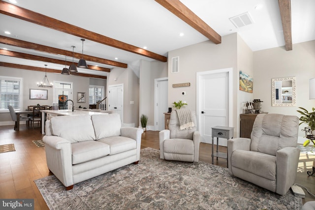 living room featuring dark hardwood / wood-style floors, beam ceiling, and a chandelier