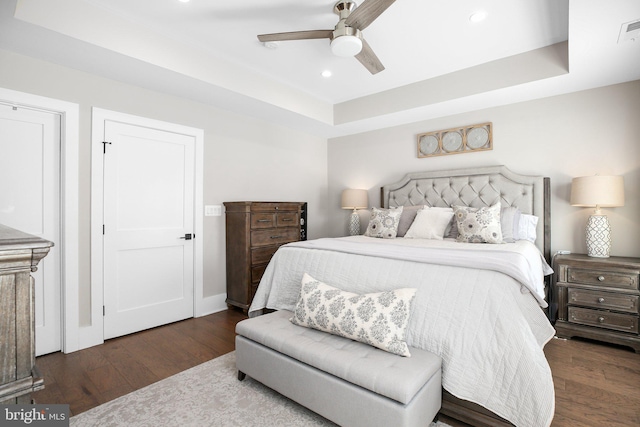 bedroom featuring ceiling fan, a tray ceiling, and dark hardwood / wood-style floors