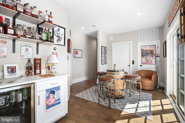 bar with dark wood-type flooring and white cabinetry