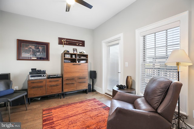 living area with wood-type flooring and ceiling fan