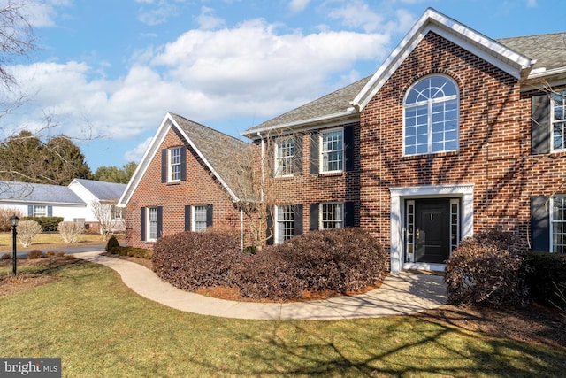 view of front of property featuring a front lawn and brick siding