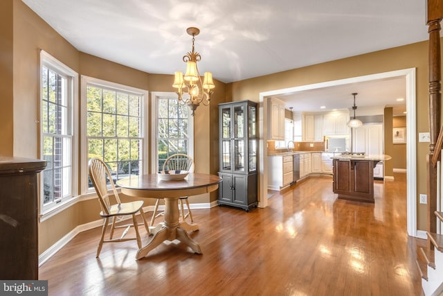 dining room with a notable chandelier, baseboards, and dark wood-type flooring