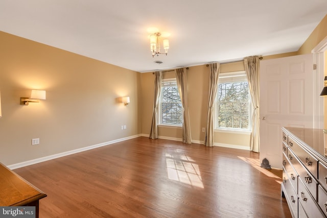 interior space with dark wood-type flooring, an inviting chandelier, and baseboards