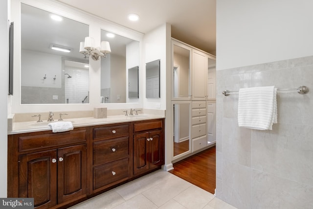 bathroom featuring double vanity, tile patterned flooring, a sink, and tiled shower