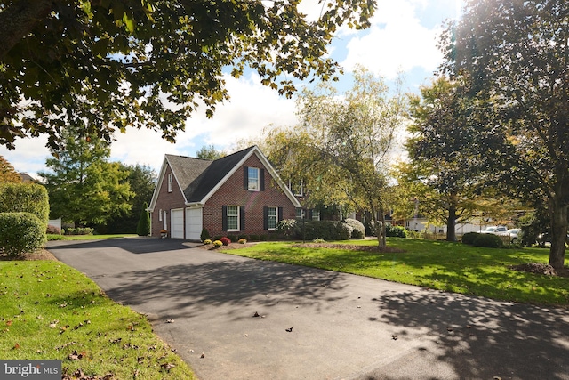 view of front of home with a front yard, brick siding, and driveway