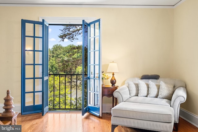 sitting room with wood-type flooring and crown molding