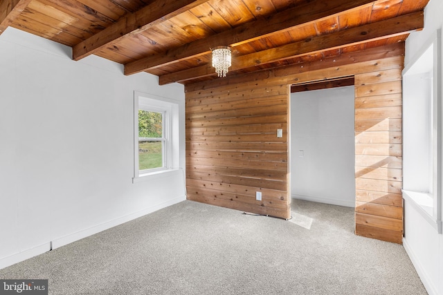 carpeted spare room featuring wood walls, beamed ceiling, a chandelier, and wooden ceiling