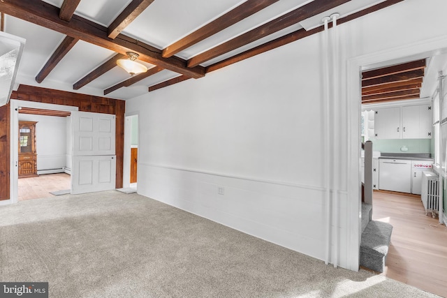 empty room with beam ceiling, a baseboard heating unit, and light hardwood / wood-style floors