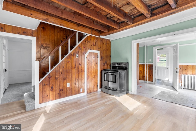 unfurnished living room featuring beam ceiling, light hardwood / wood-style flooring, wooden walls, and radiator heating unit