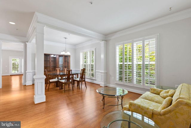 living room featuring ornamental molding, a chandelier, light hardwood / wood-style flooring, and a wealth of natural light