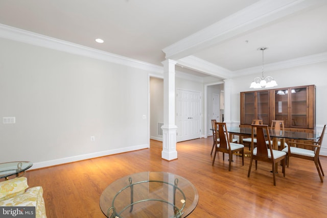 dining area featuring ornate columns, hardwood / wood-style flooring, crown molding, and a chandelier