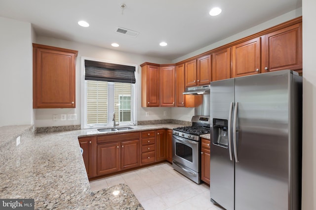 kitchen featuring light stone countertops, stainless steel appliances, sink, and kitchen peninsula