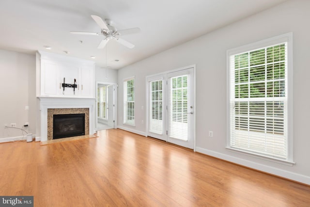 unfurnished living room featuring a fireplace, ceiling fan, and light hardwood / wood-style floors