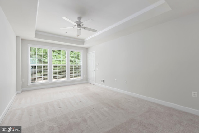 unfurnished room featuring ceiling fan, a tray ceiling, and light carpet