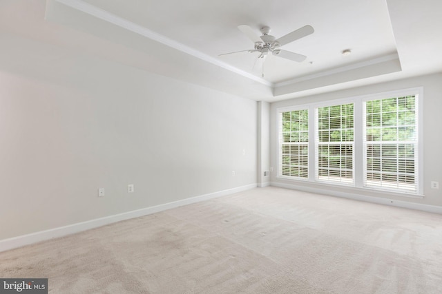 spare room with ceiling fan, crown molding, a tray ceiling, and light colored carpet