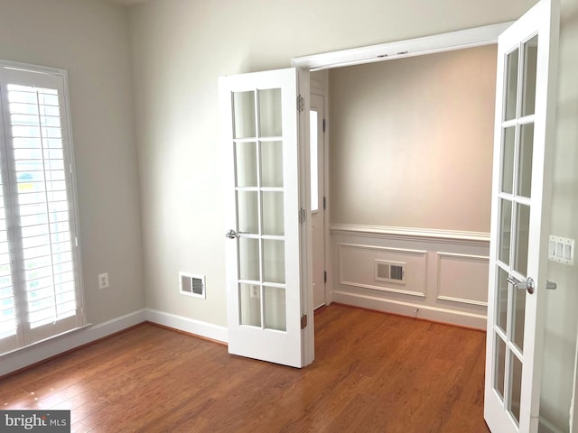 empty room with french doors, hardwood / wood-style flooring, and plenty of natural light