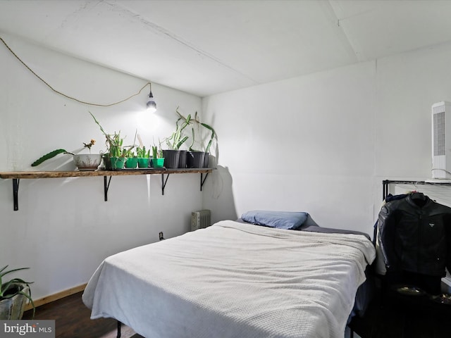 bedroom with radiator heating unit and dark hardwood / wood-style flooring