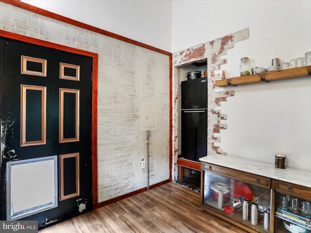 foyer entrance with brick wall and hardwood / wood-style flooring