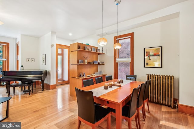 dining room featuring radiator heating unit and light wood-type flooring