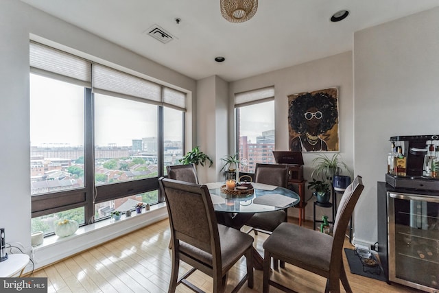 dining area with plenty of natural light, wine cooler, and light wood-type flooring