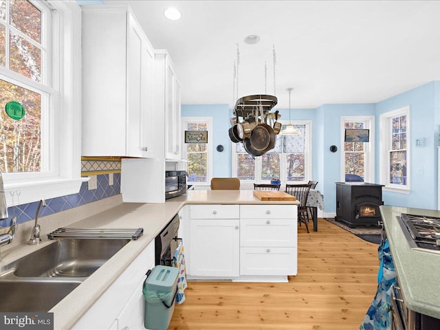 kitchen with white cabinetry, decorative backsplash, light hardwood / wood-style flooring, and hanging light fixtures