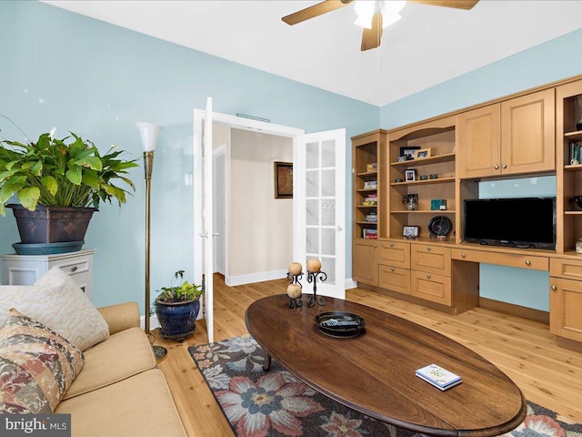 living room featuring built in desk, ceiling fan, and light hardwood / wood-style flooring