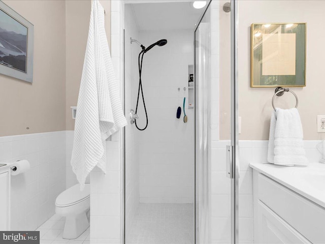 bathroom featuring vanity, toilet, an enclosed shower, and tile walls