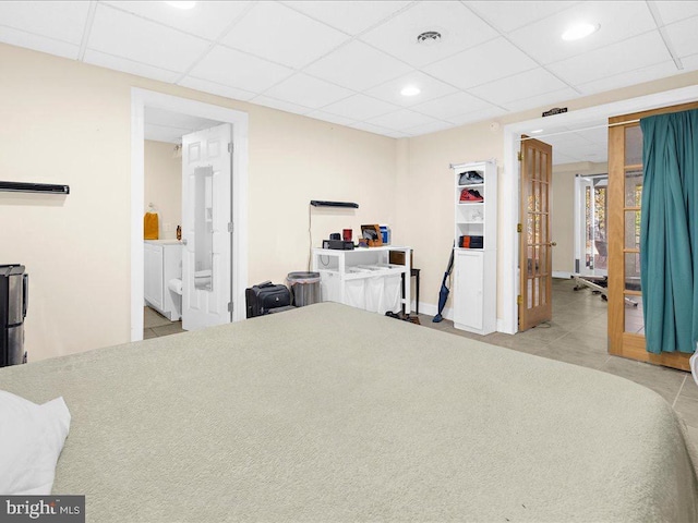 bedroom featuring ensuite bathroom, a paneled ceiling, and light tile patterned flooring