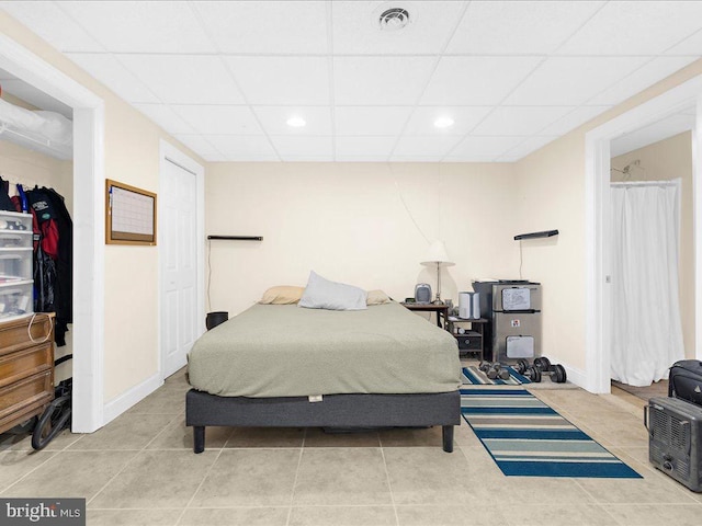 bedroom with a paneled ceiling and light tile patterned floors