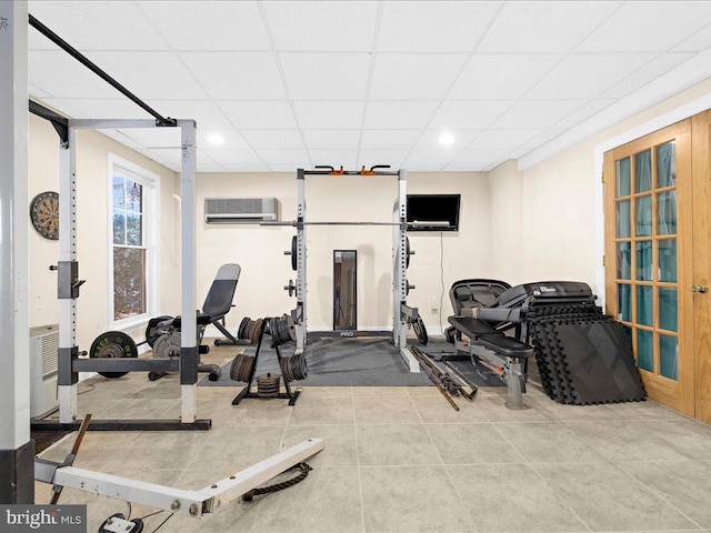 exercise room with a paneled ceiling, tile patterned flooring, and a wall mounted air conditioner