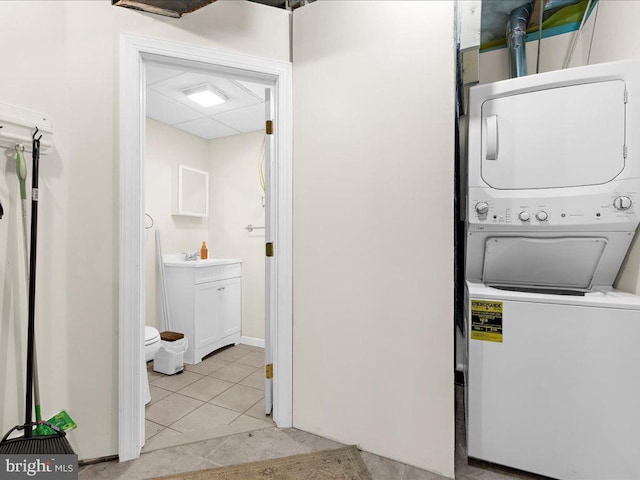 washroom featuring light tile patterned flooring, sink, and stacked washer and dryer