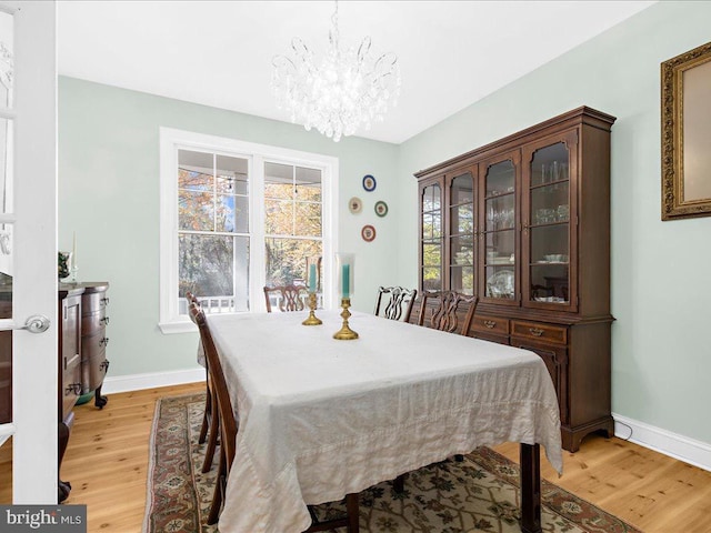 dining area with light wood-type flooring and a notable chandelier