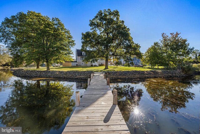 view of dock with a water view and a lawn