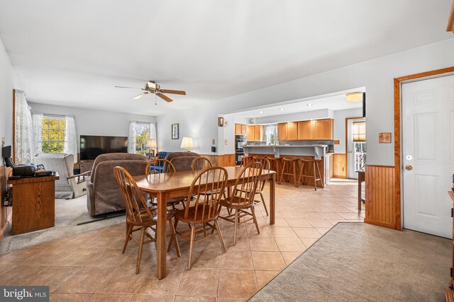 dining space featuring ceiling fan, wood walls, and light tile patterned floors