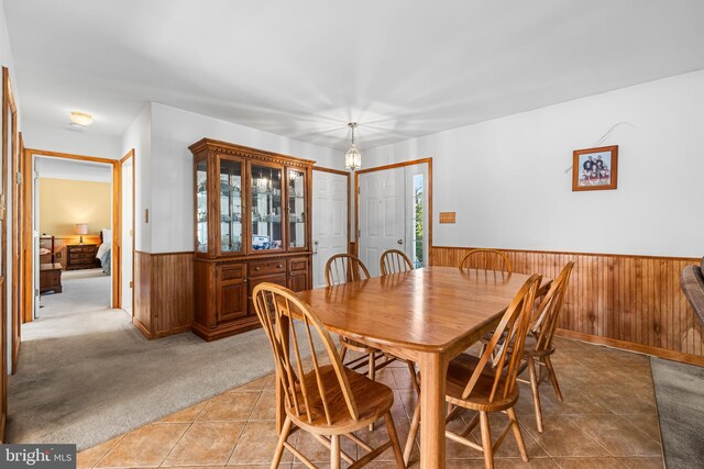 carpeted dining room with wood walls