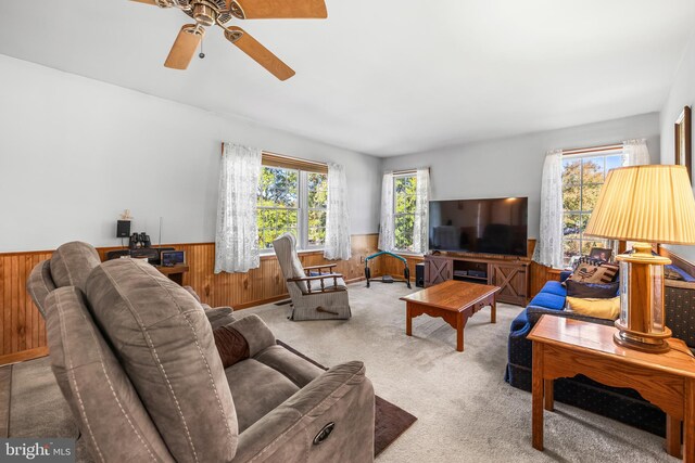 living room with wooden walls, carpet, a healthy amount of sunlight, and ceiling fan