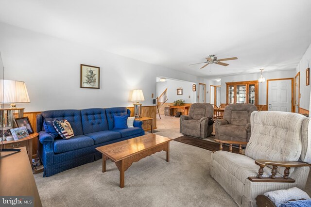 living room featuring wooden walls, light carpet, and ceiling fan