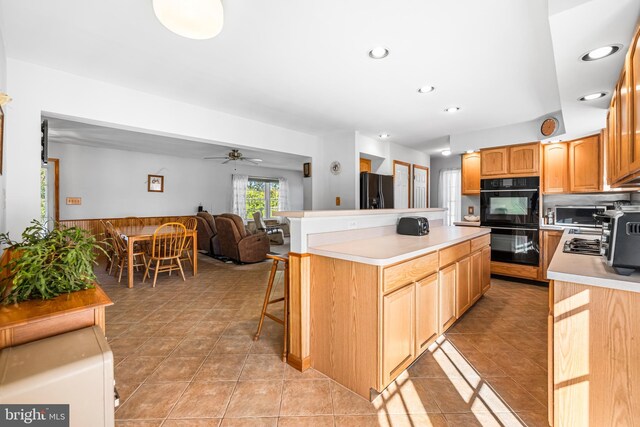 kitchen featuring a kitchen breakfast bar, black appliances, light tile patterned floors, and ceiling fan