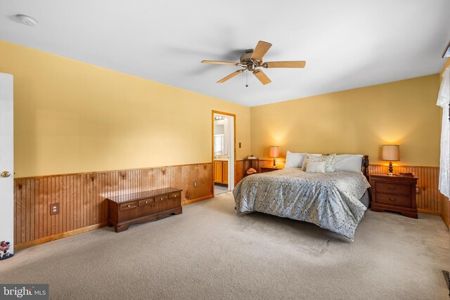 carpeted bedroom featuring ceiling fan and wood walls