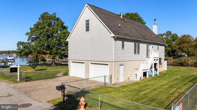 view of side of home with a lawn, a garage, and a water view