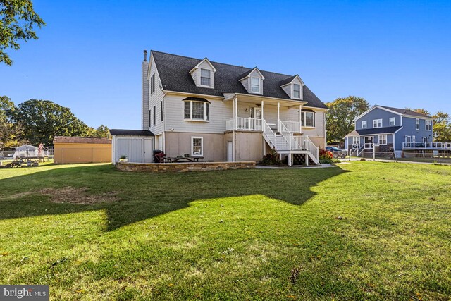 rear view of property with a storage unit and a lawn