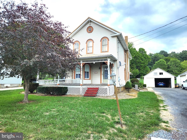 view of front of house featuring a front yard, an outbuilding, a garage, and covered porch