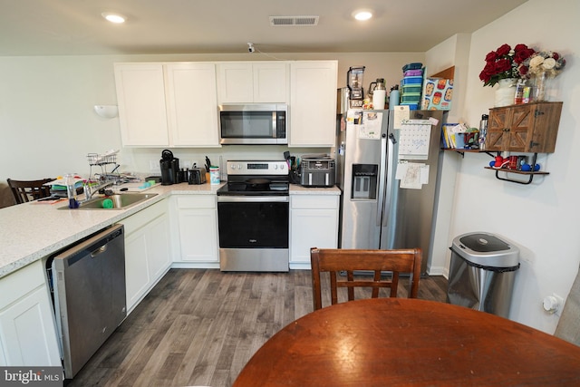 kitchen featuring appliances with stainless steel finishes, sink, dark hardwood / wood-style floors, and white cabinets