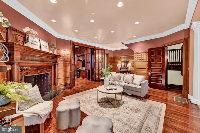 living room with ornamental molding, wood-type flooring, and ornate columns