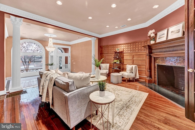 living room featuring crown molding, hardwood / wood-style flooring, and decorative columns