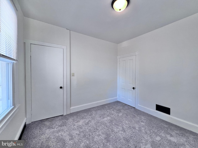 unfurnished bedroom with baseboards, carpet flooring, multiple windows, and a closet